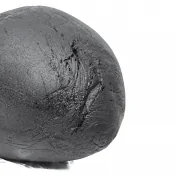 Boule de résine CBD noire texturée, aspect rugueux et mat, sur fond blanc